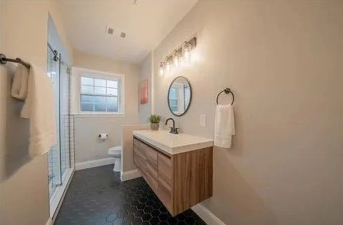 A bathroom with a sink , toilet and mirror.