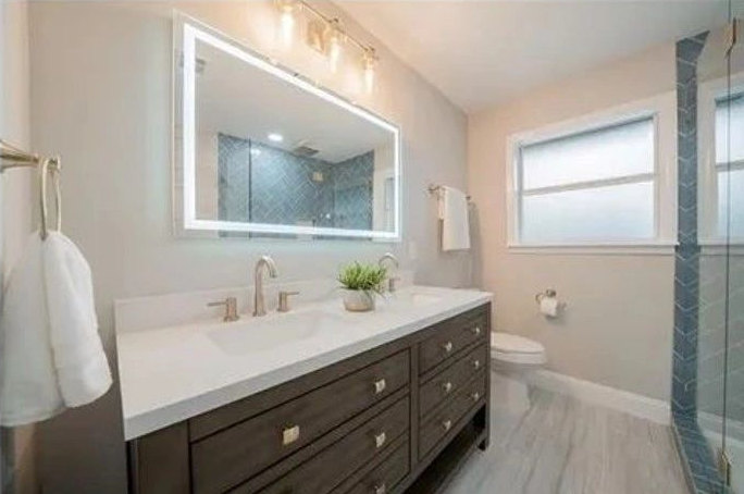 A bathroom with two sinks , a toilet , and a large mirror.