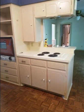 A kitchen with white cabinets and a stove top oven