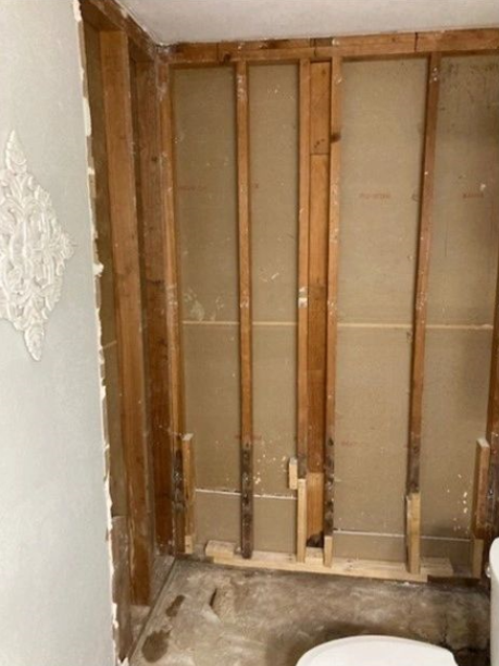 A bathroom with a toilet and a wooden wall.