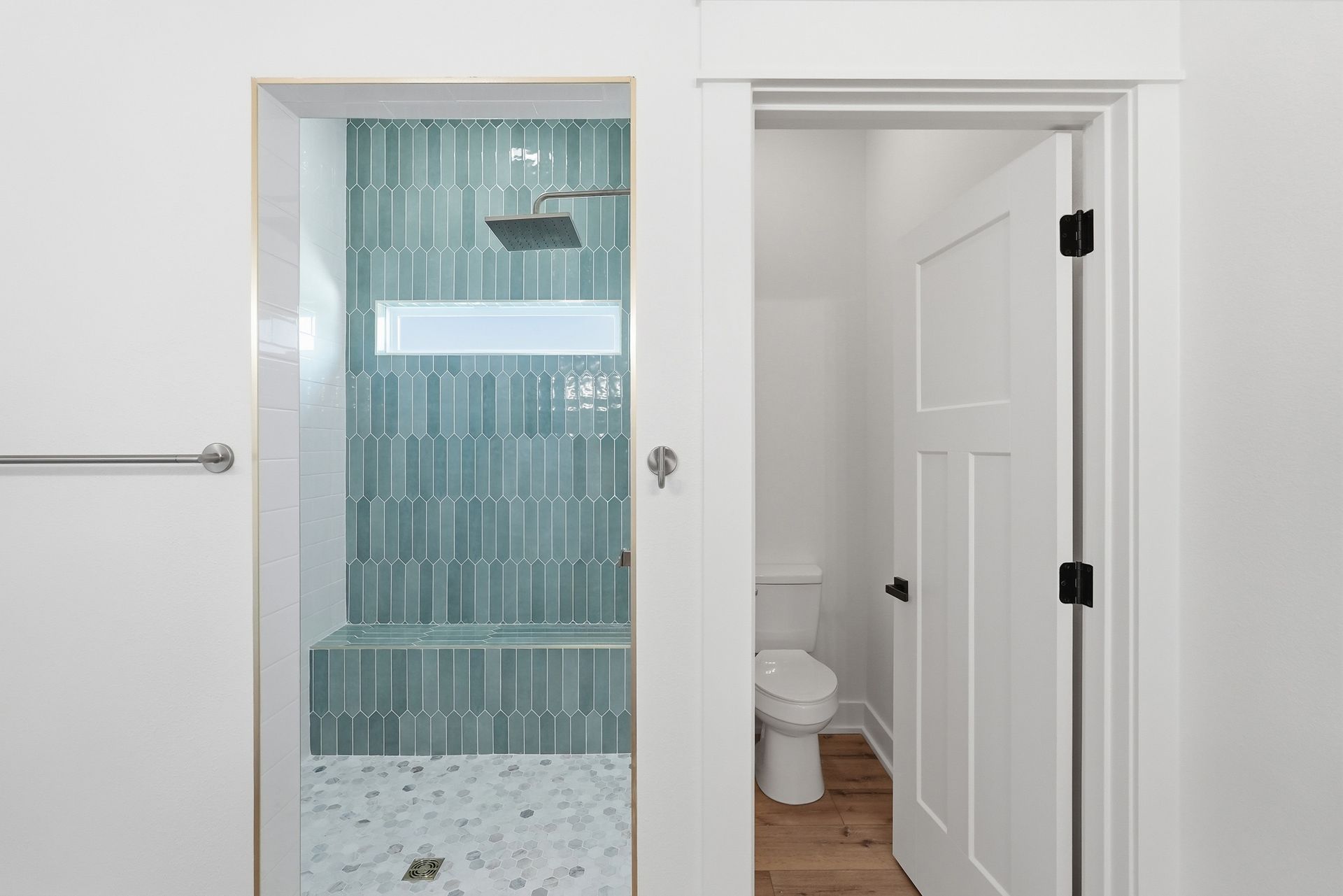 Bathroom with glass shower on the left and open toilet room on the right