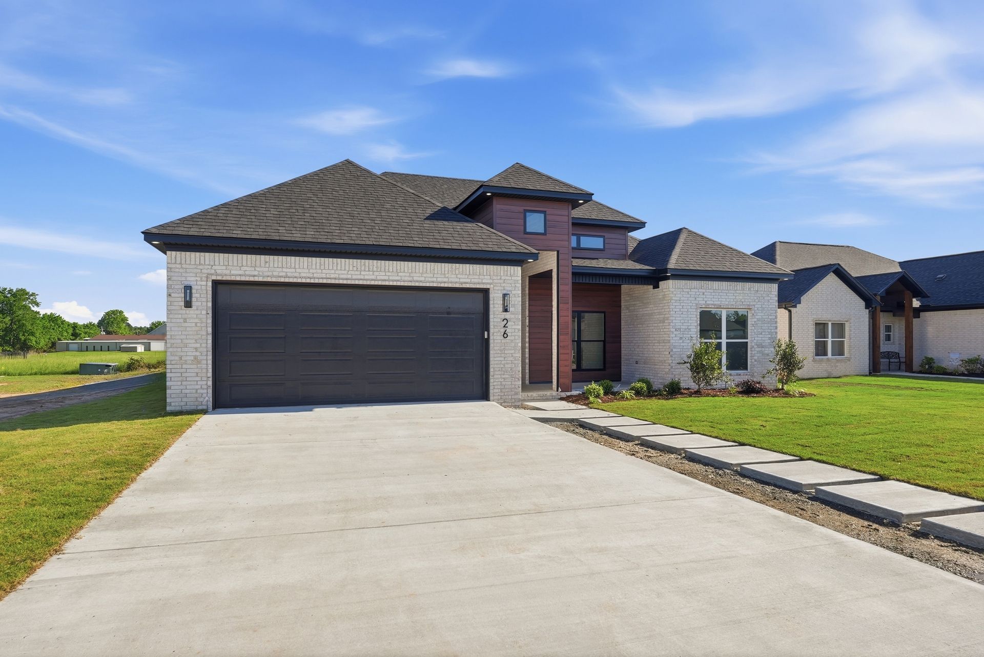 Modern house entrance with white stone siding, dark wood-paneled walls, black-framed windows, and a black front door.