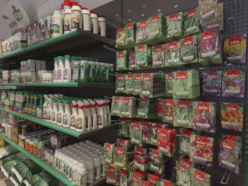 Corridoio del negozio con scaffali pieni di prodotti confezionati in verde e rosso e articoli per la pulizia.