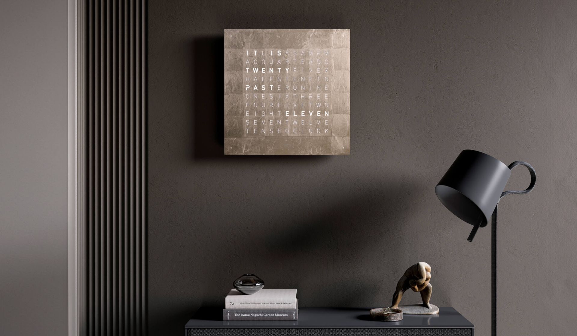 Donkere muur met ingelijste kunstwerken, boeken, een lamp en een sculptuur op een consoletafel.