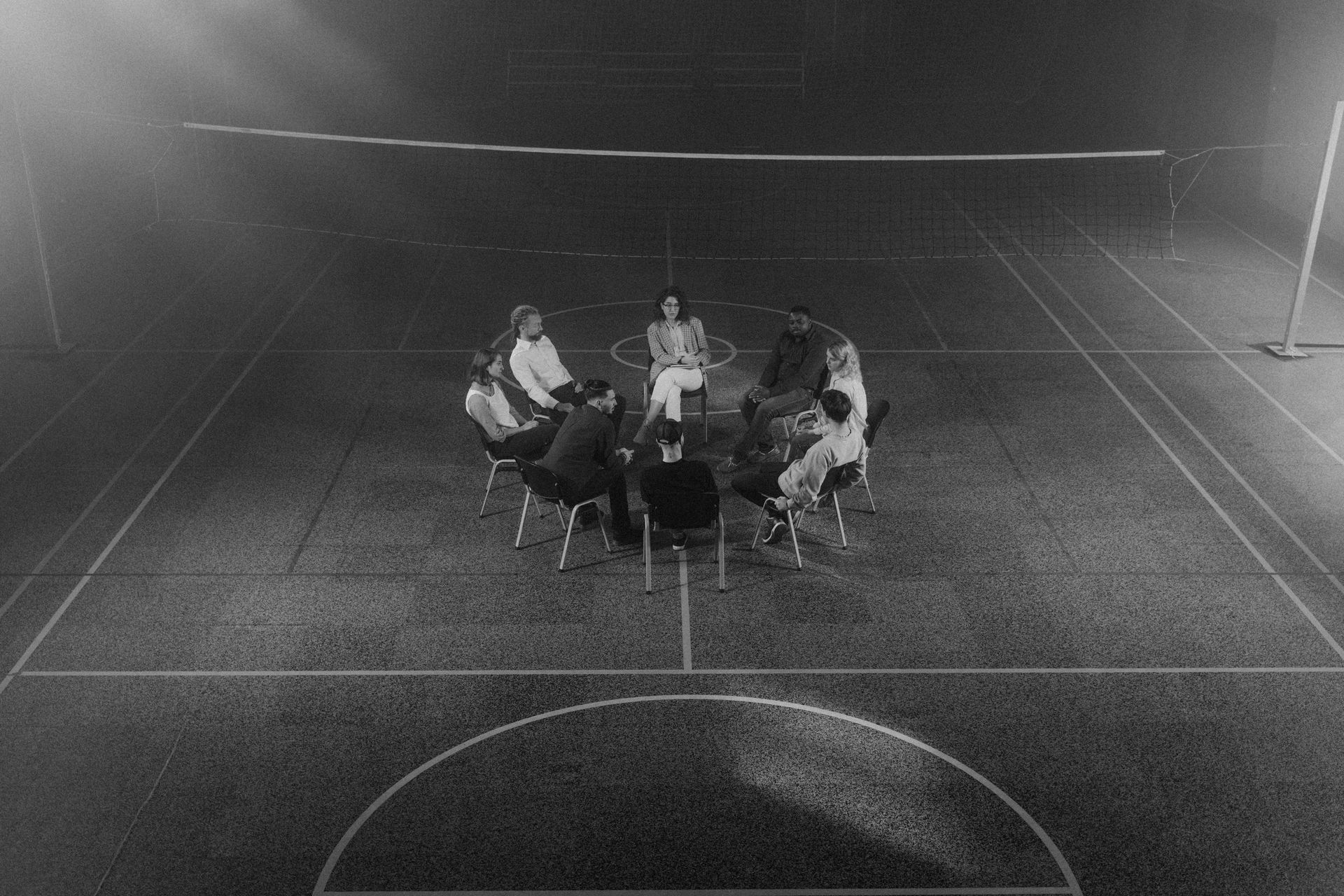 People seated in a circle on an outdoor sports field at night