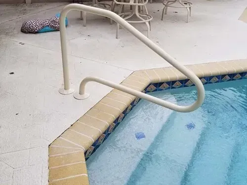 A white railing is attached to the side of a swimming pool.