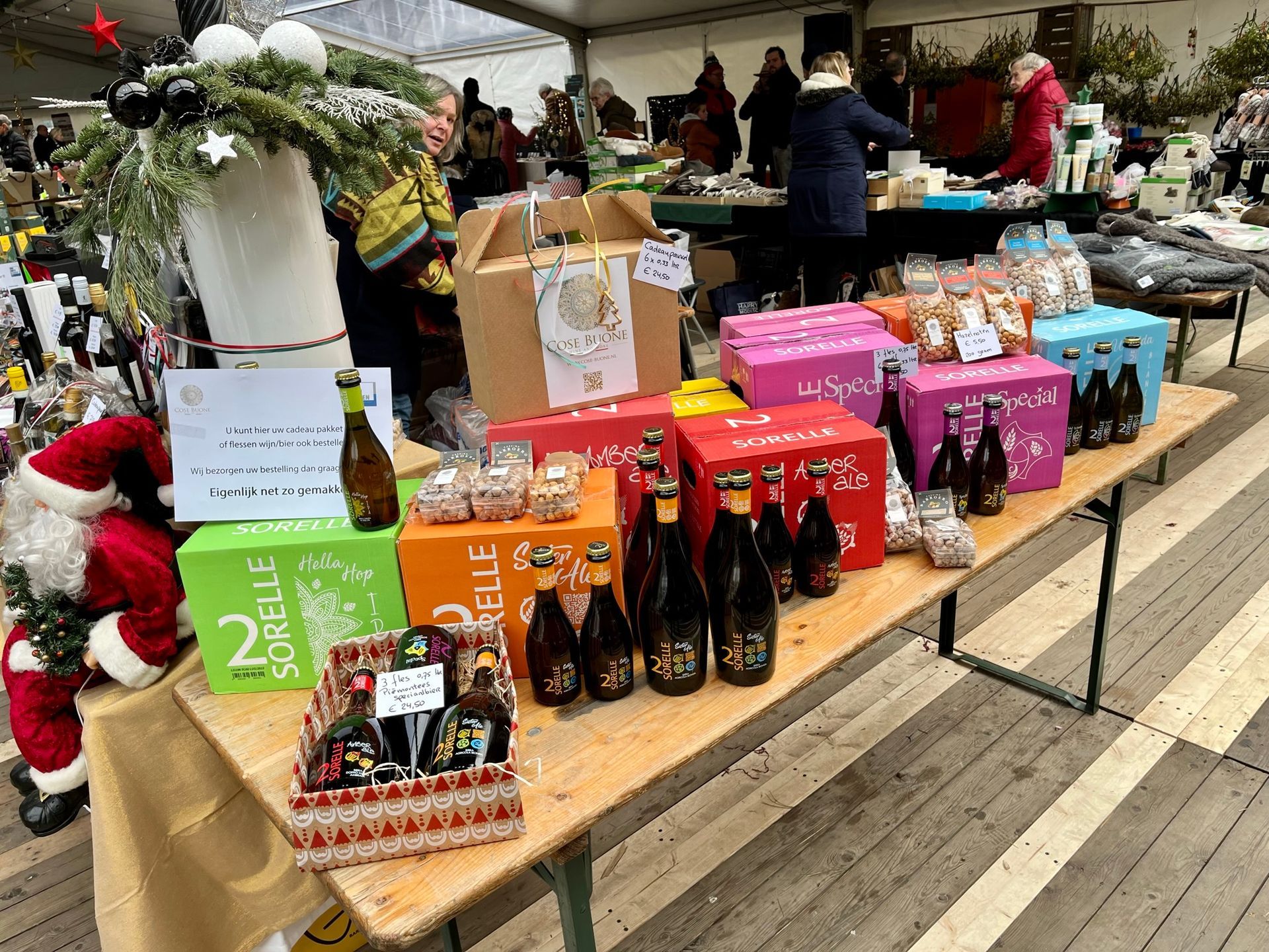 Kerstmarkt met een uitstalling van cadeausets, flessen drank en kerstmanversieringen.
