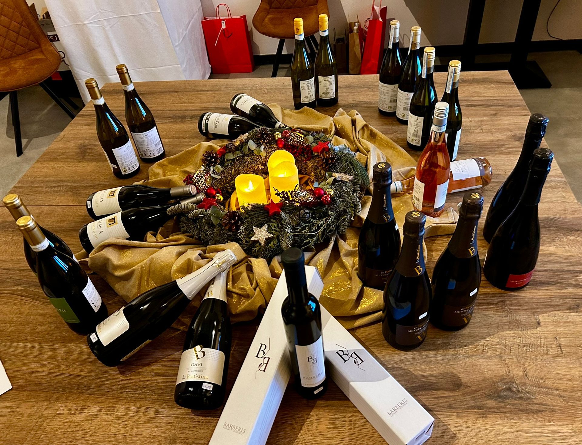 Houten tafel met wijnflessen en een kerstkrans als middelpunt, feestelijke setting.