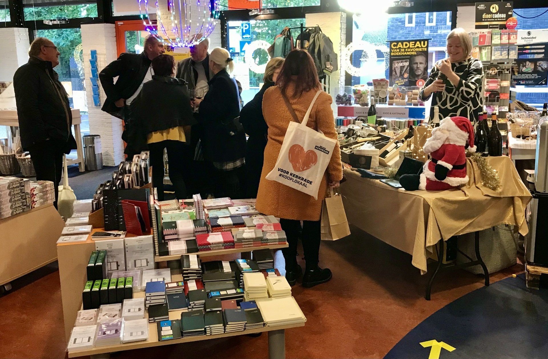 Mensen bekijken de koopwaar op een ambachtsmarkt; op verschillende tafels staan diverse artikelen uitgestald.