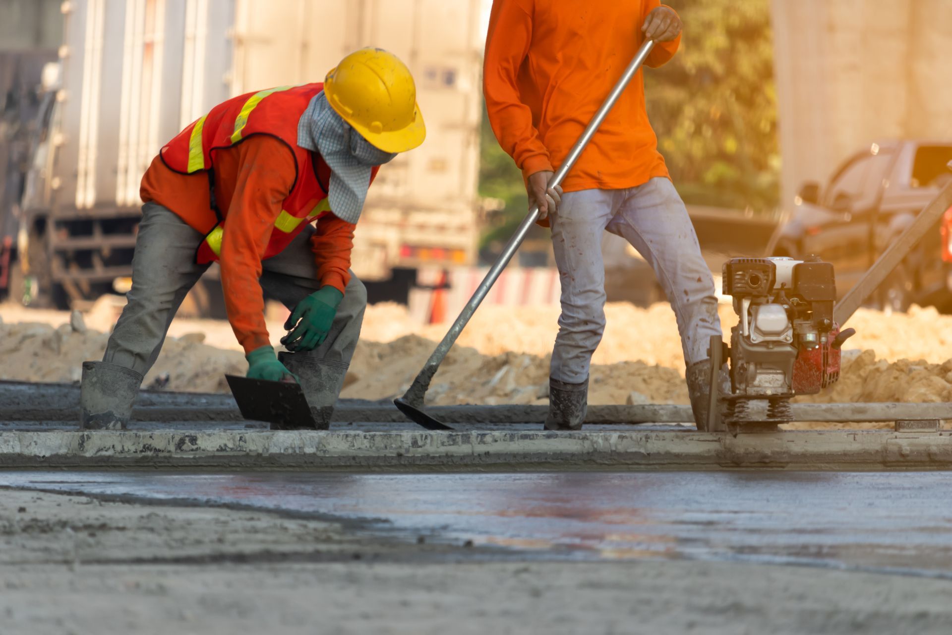 Construction workers smoothing wet concrete with a trowel on a road site