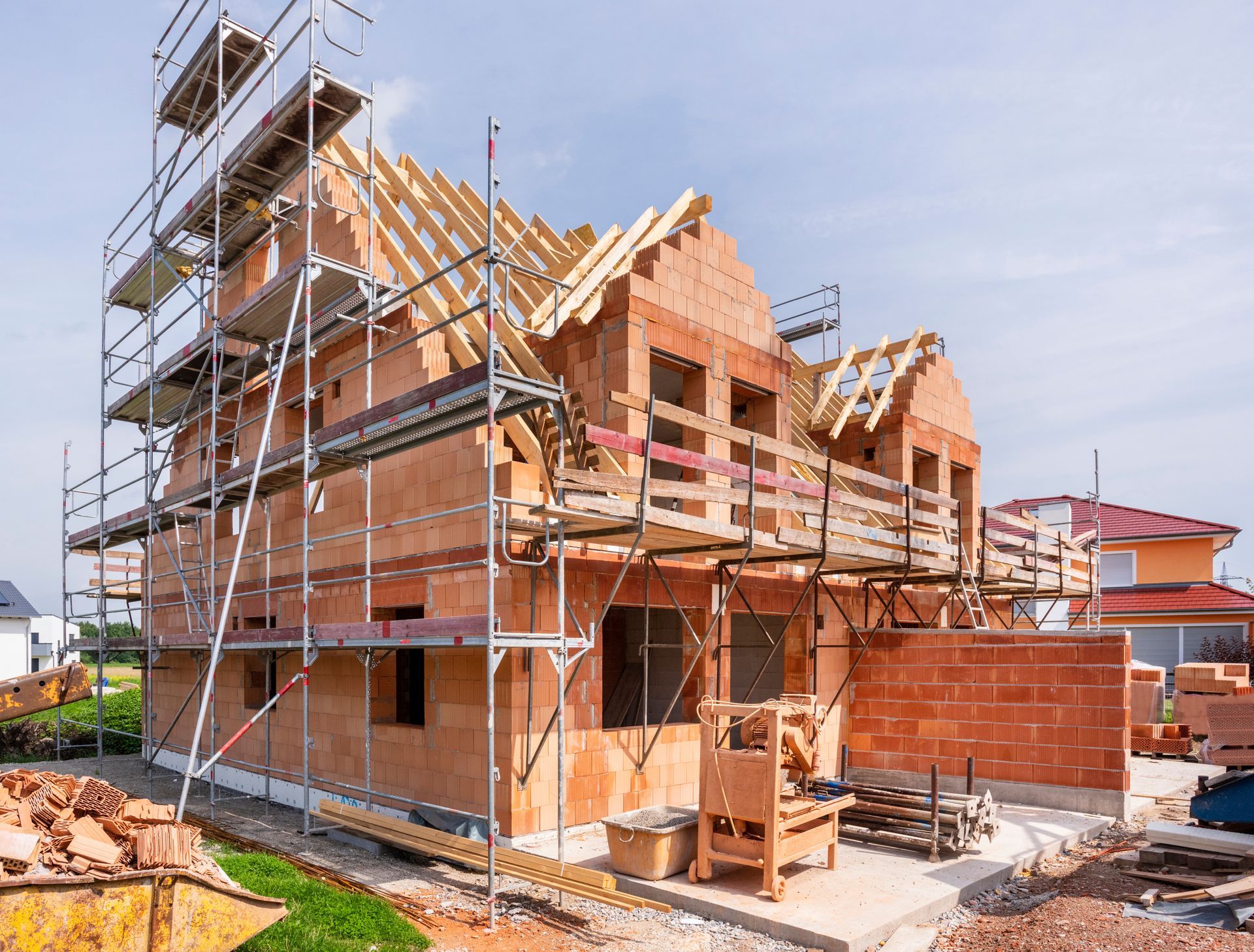 Brick house under construction with scaffolding and partially framed roof