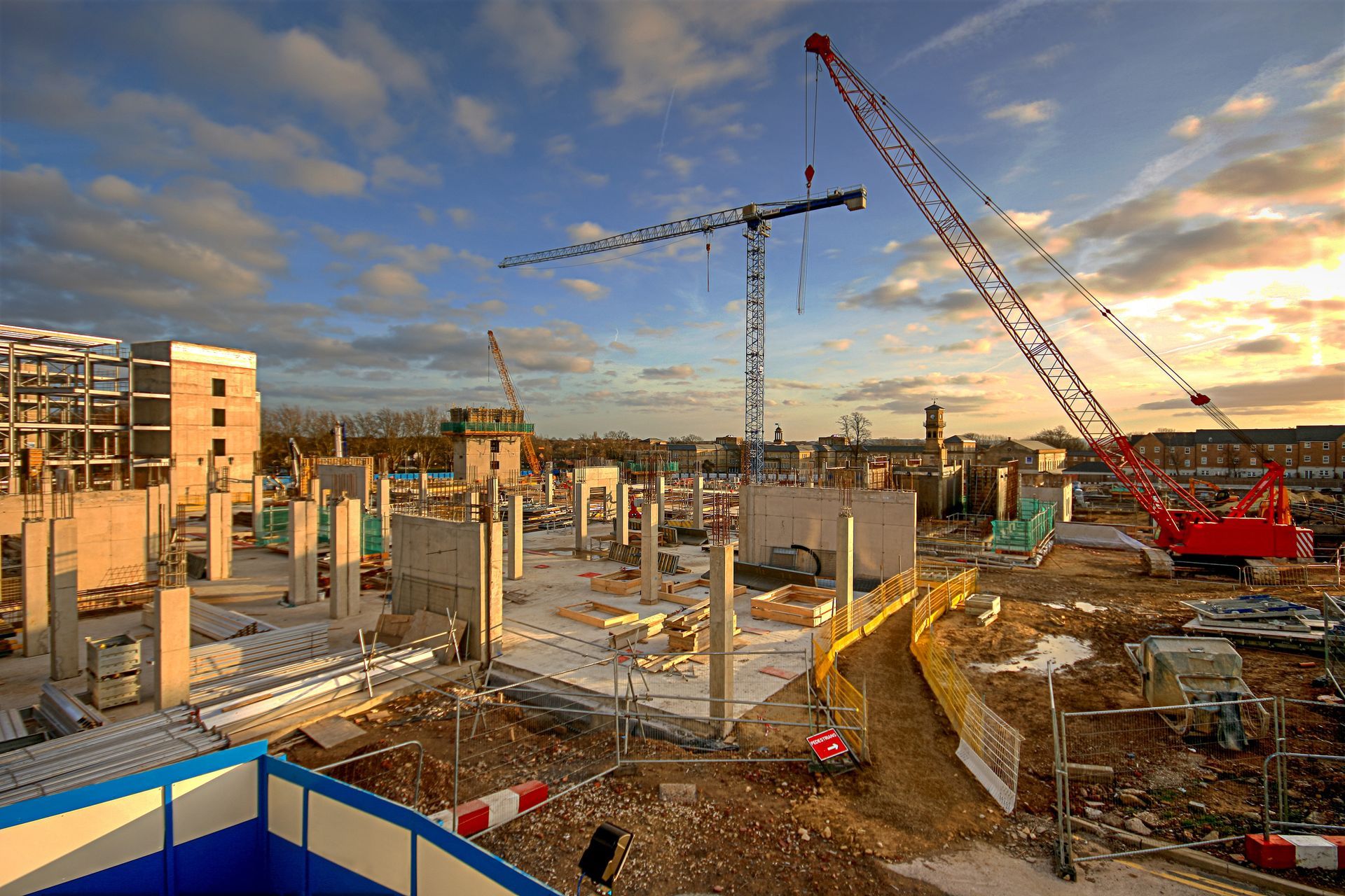 Construction site with cranes and concrete columns at sunset
