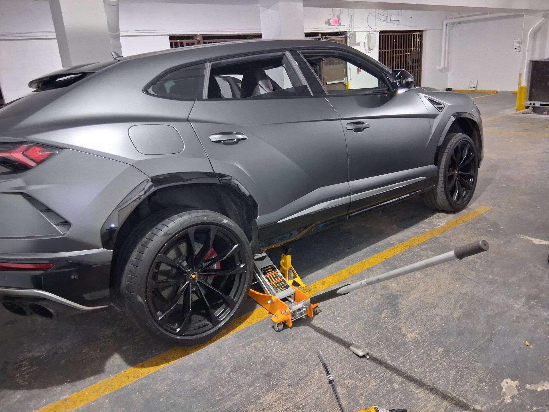 Gray SUV in a parking garage, with a wheel clamp attached to the rear wheel.