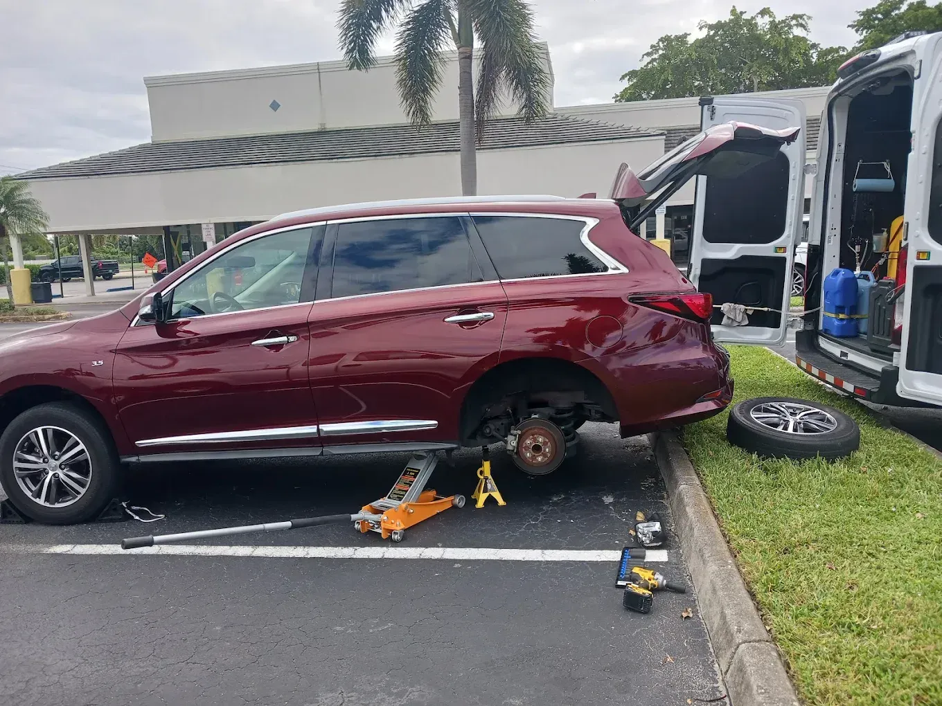 Flat tire on a car parked on a gravel roadside, with another car in the background.