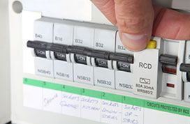 Hand Flipping A Circuit Breaker Switch In A White Electrical Panel — Stellar Test and Tag in Gunnedah, NSW