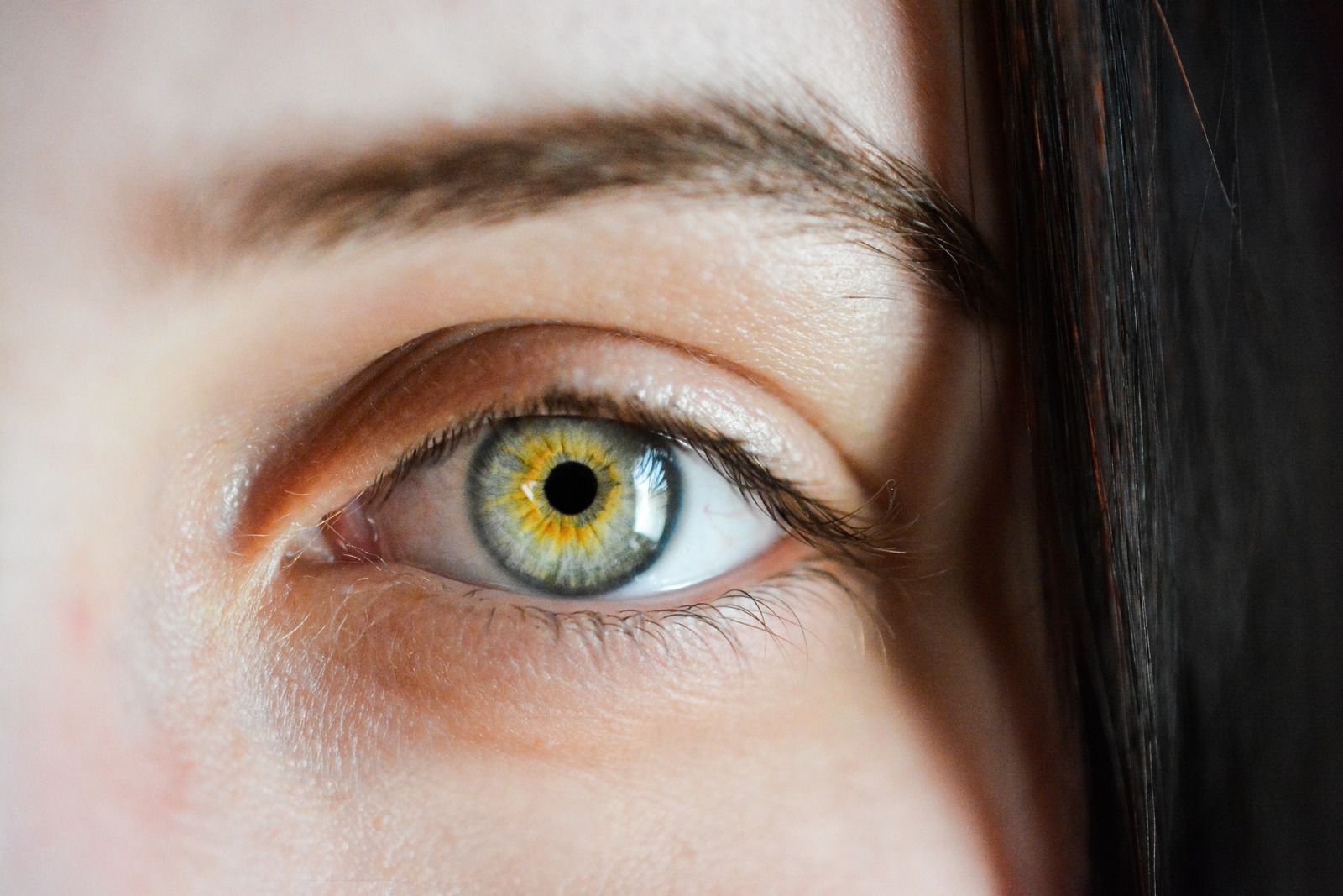 A close up of a woman 's green eye with a yellow pupil.