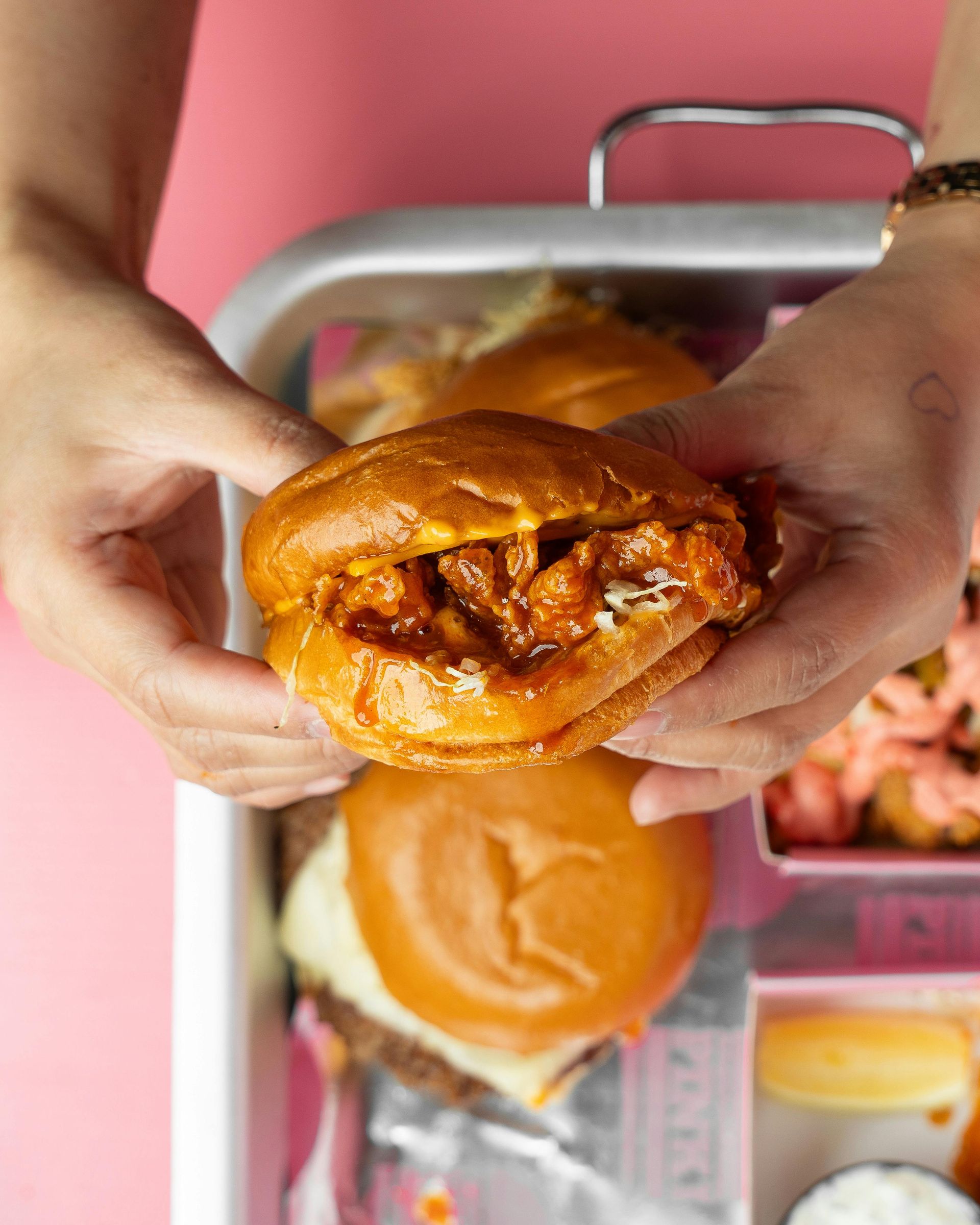 A person is holding a chicken sandwich in their hands.