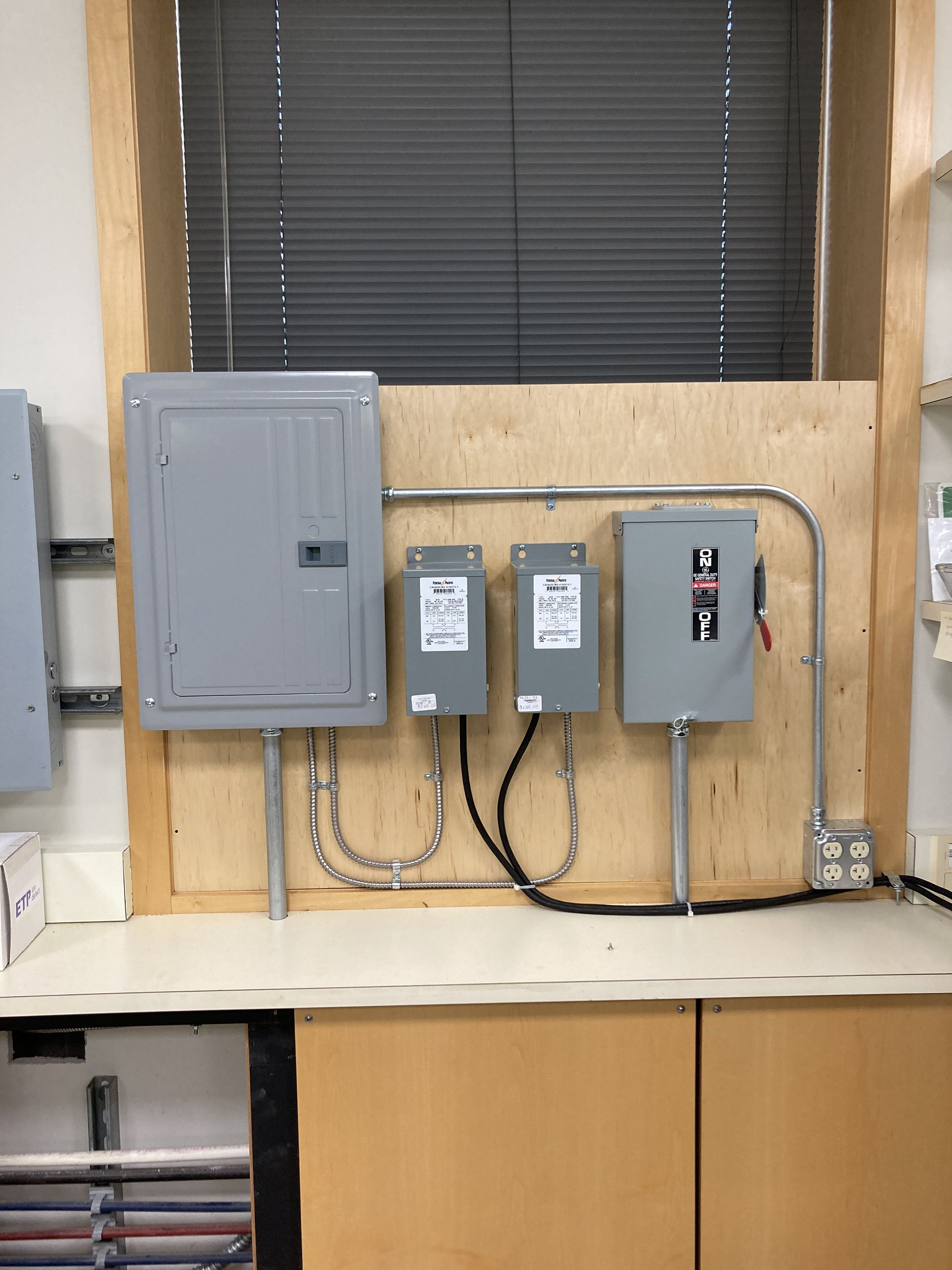 three electrical boxes on a wooden wall one of which has a warning label on it