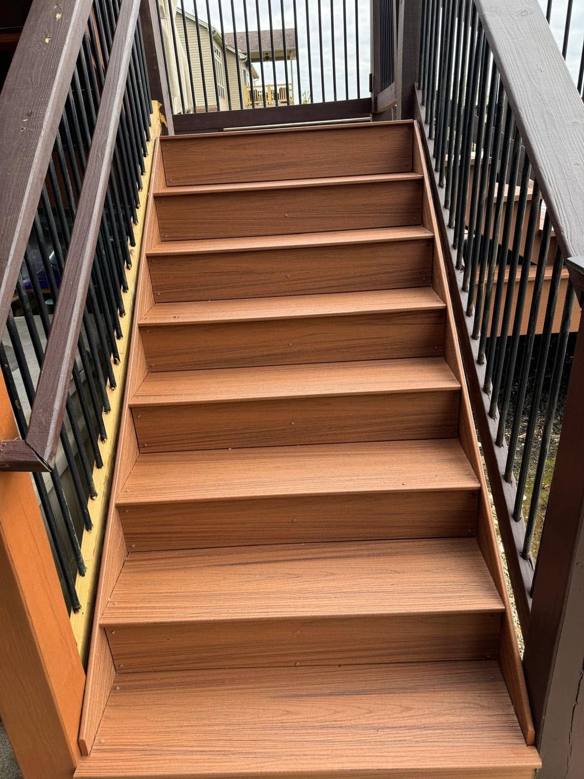 Wooden staircase with black metal railings, viewed from above.