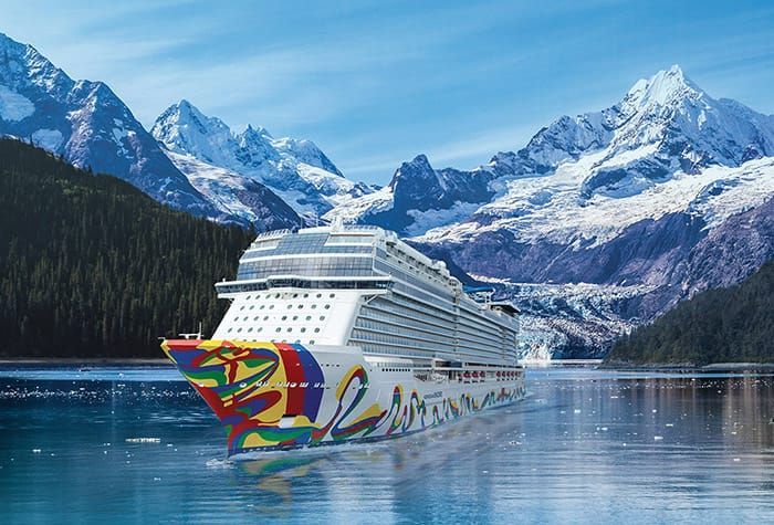 A cruise ship is floating in a body of water with mountains in the background