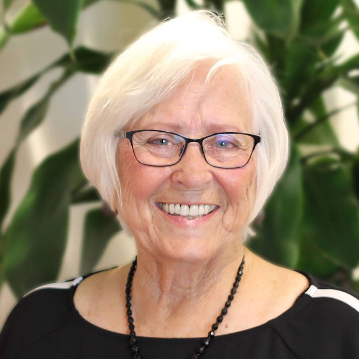 a woman wearing glasses and a necklace smiles for the camera
