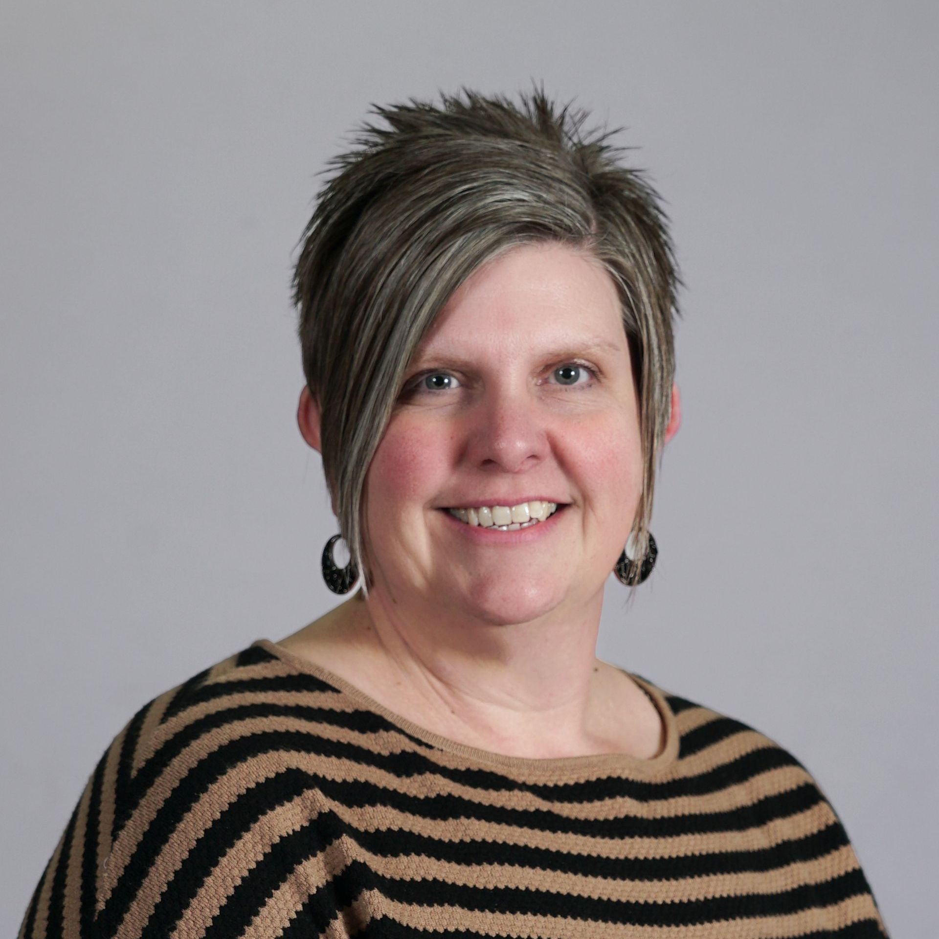 A woman wearing a blue shirt and a black jacket is smiling for the camera.