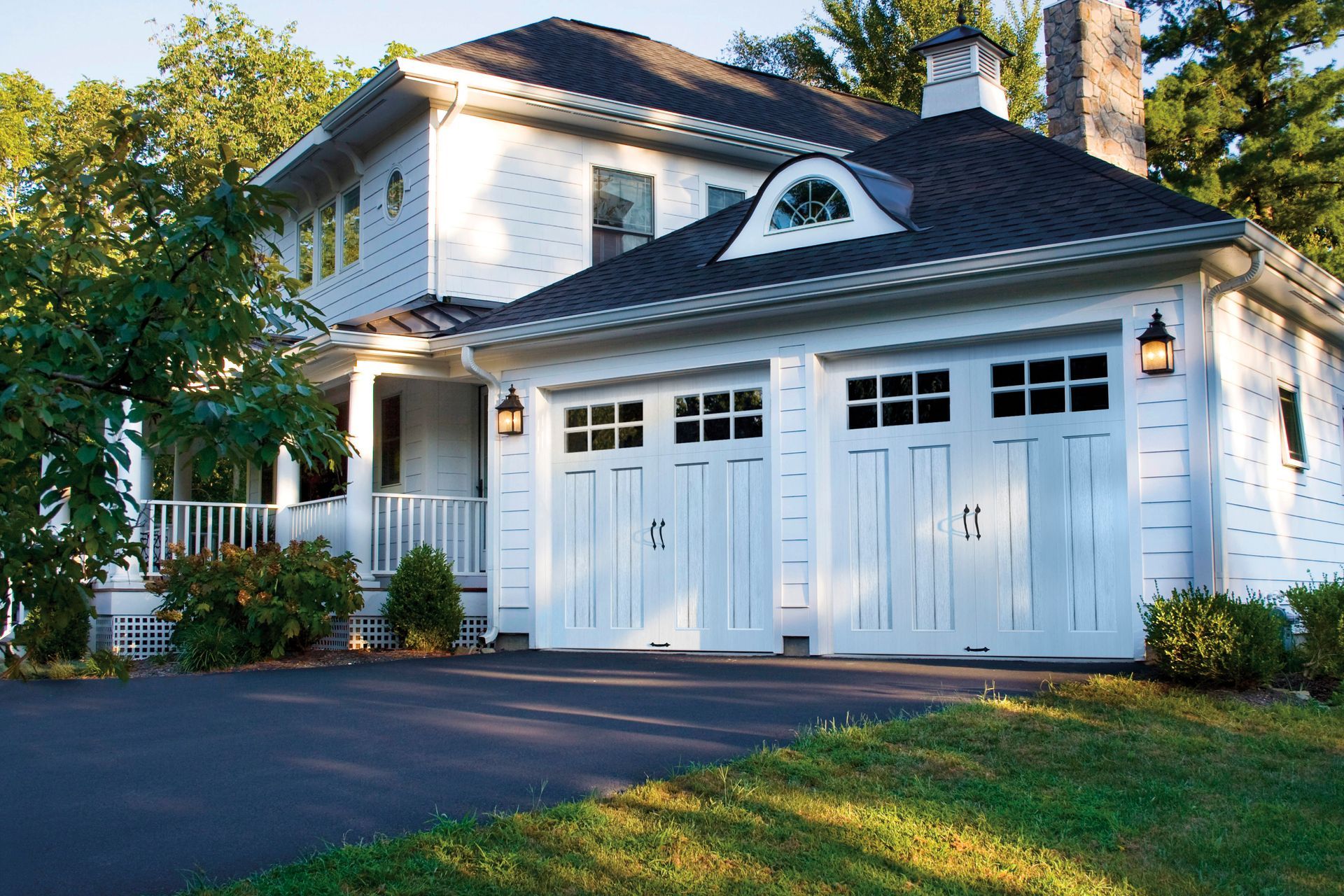 A large white house with a black roof and white garage doors