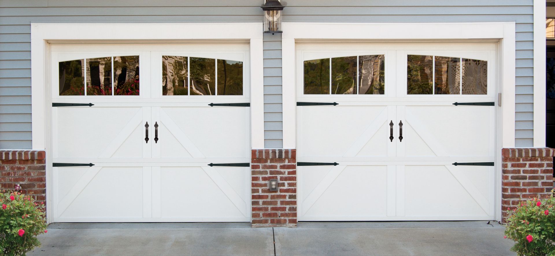 A pair of white garage doors on a brick house.
