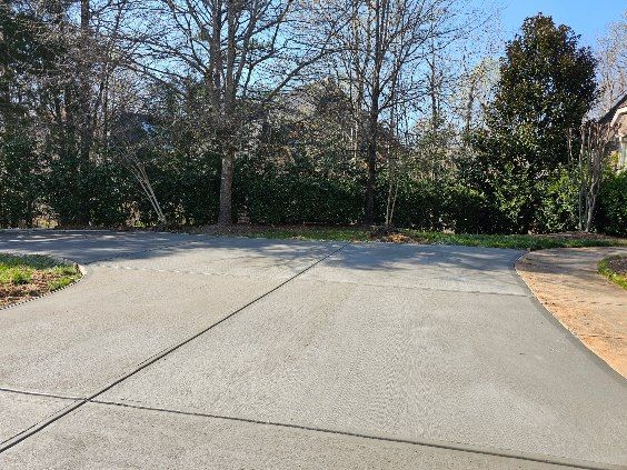Paved driveway forks, trees in the background under a blue sky.