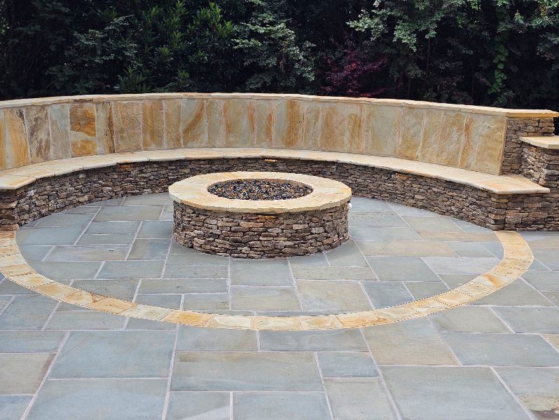 Stone fire pit with curved stone seating on a patio.