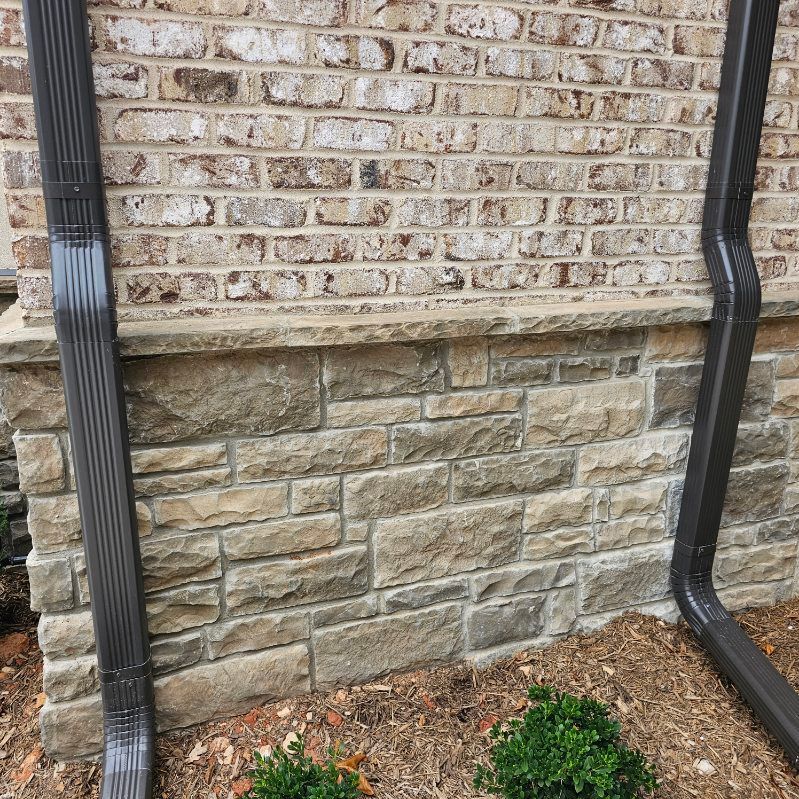 Dark gutters flank a brick and stone exterior wall.
