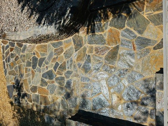 Stone wall with various colors, in an outdoor setting.