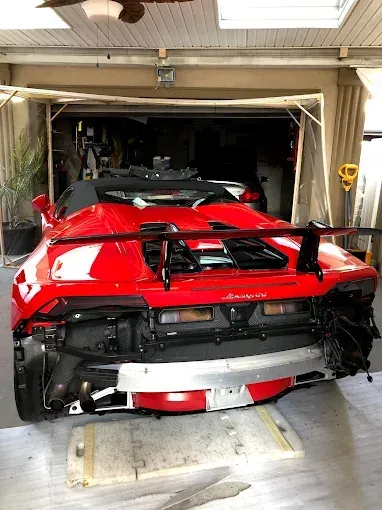 Red Lamborghini Huracan in a garage with rear bumper removed.
