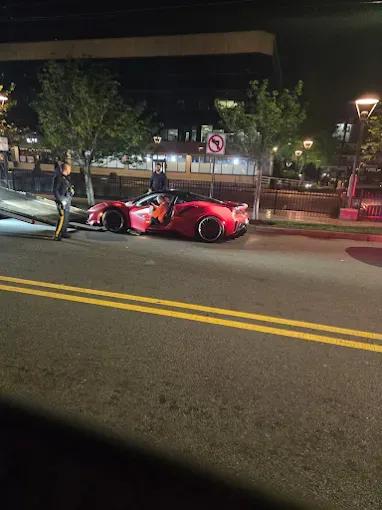 Red sports car parked on street with open door. Police officer nearby. Nighttime.