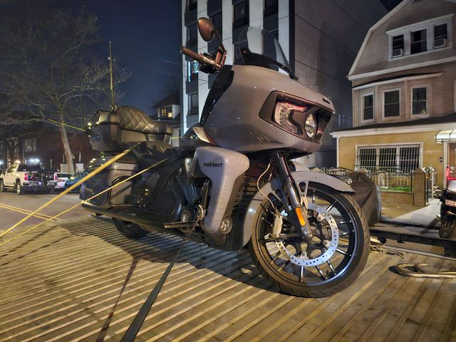 Damaged motorcycle on a tow truck at night in a residential street