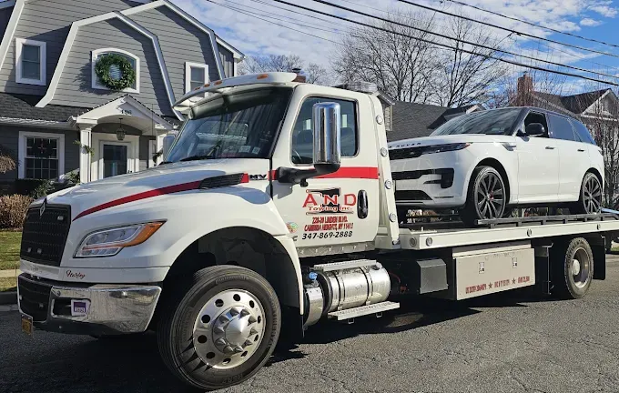 Tow truck with white SUV on its flatbed in front of a gray house.