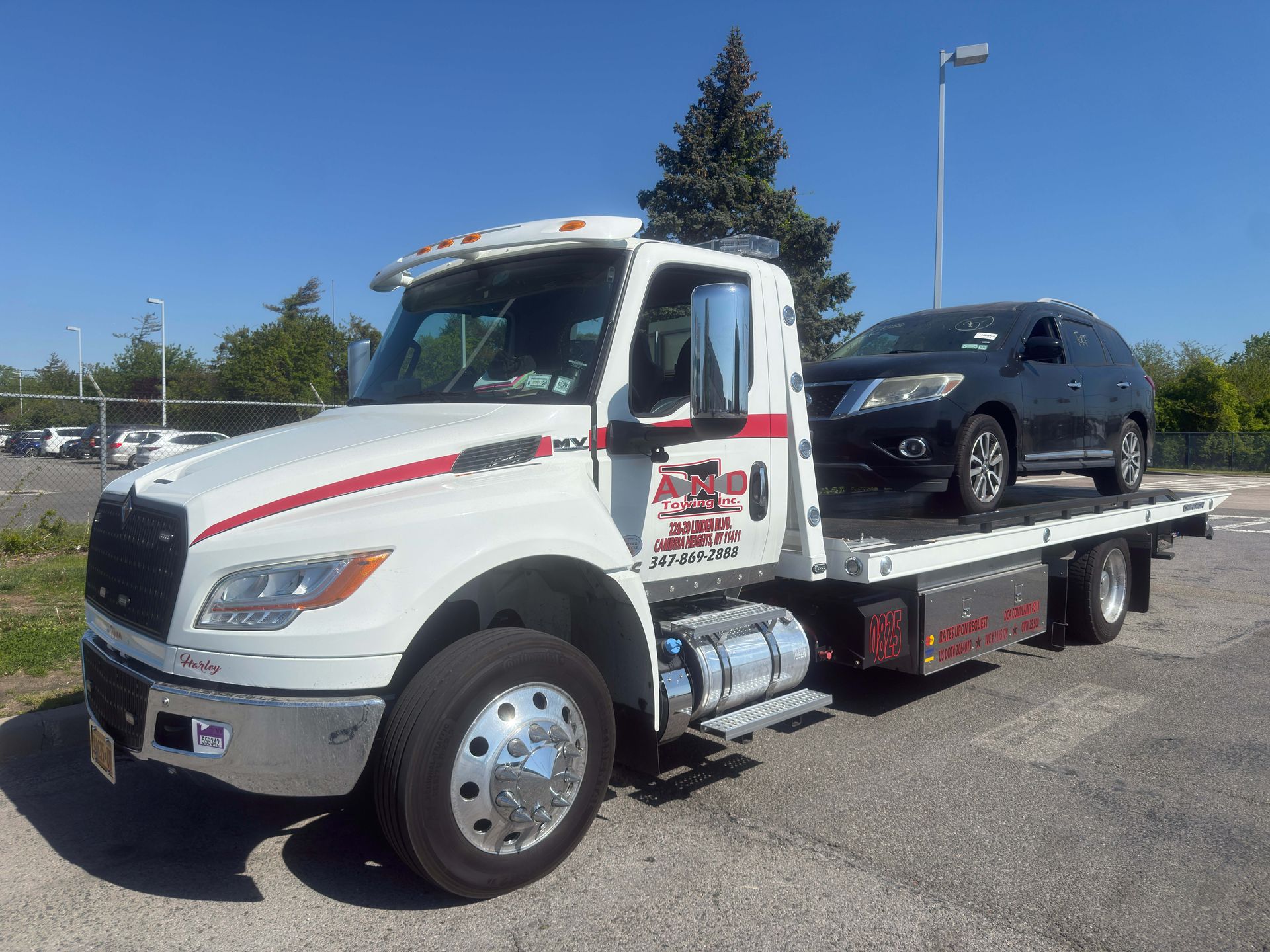 Tow truck carrying a black SUV on a flatbed under a clear blue sky