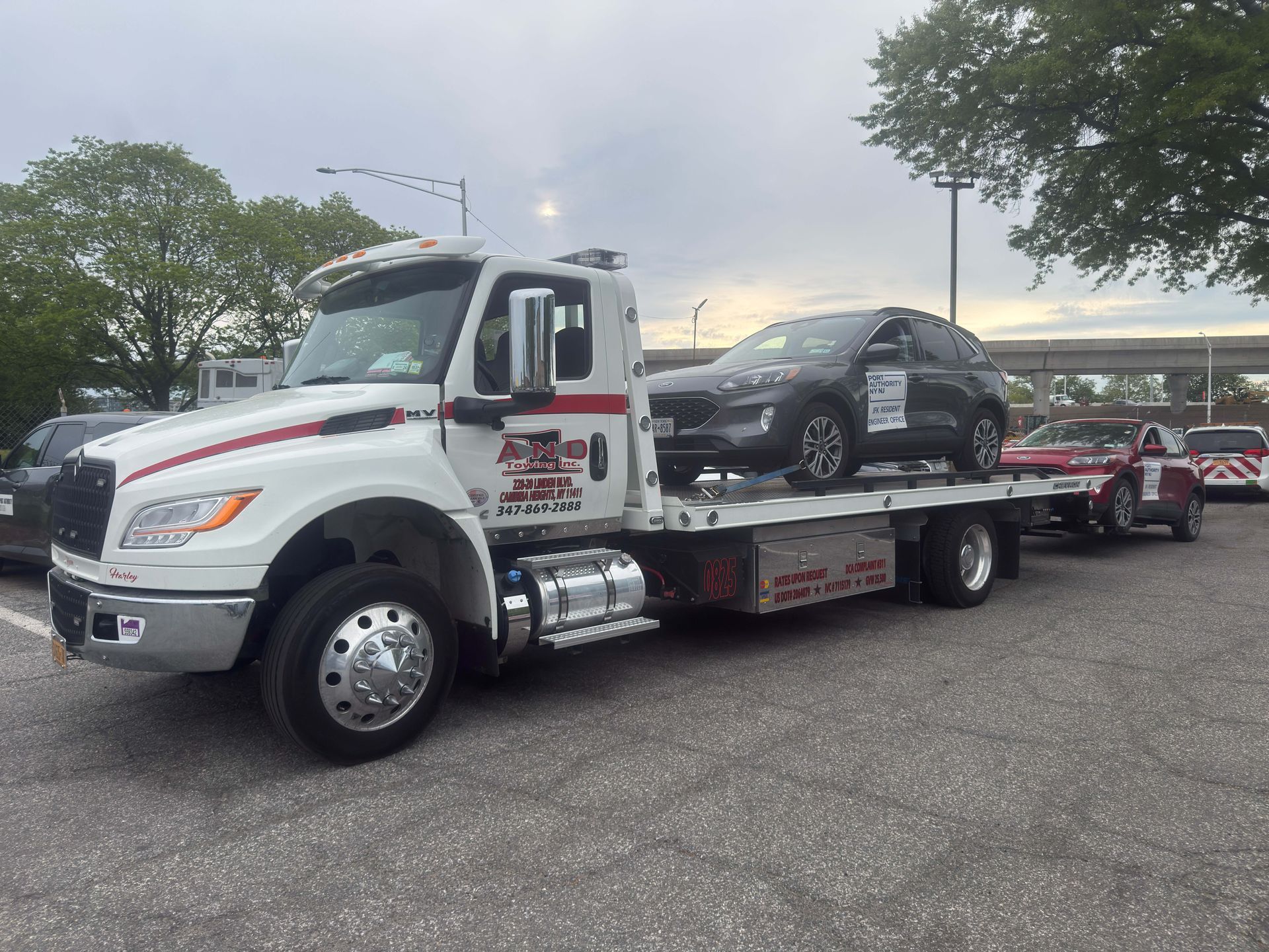 Tow truck hauling a black sedan in a parking lot at dusk