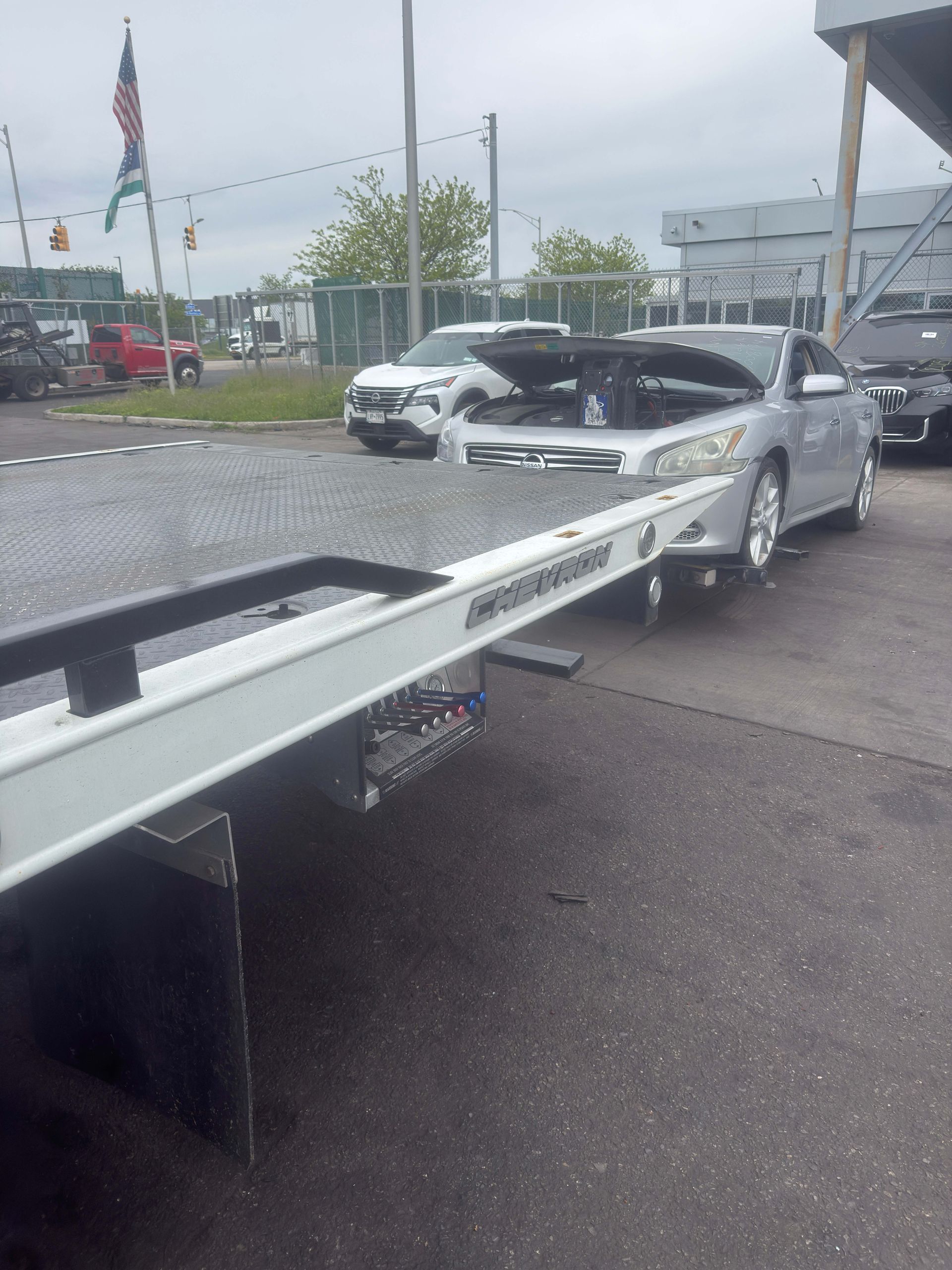 Silver sedan being loaded onto a tow truck in a wet parking lot