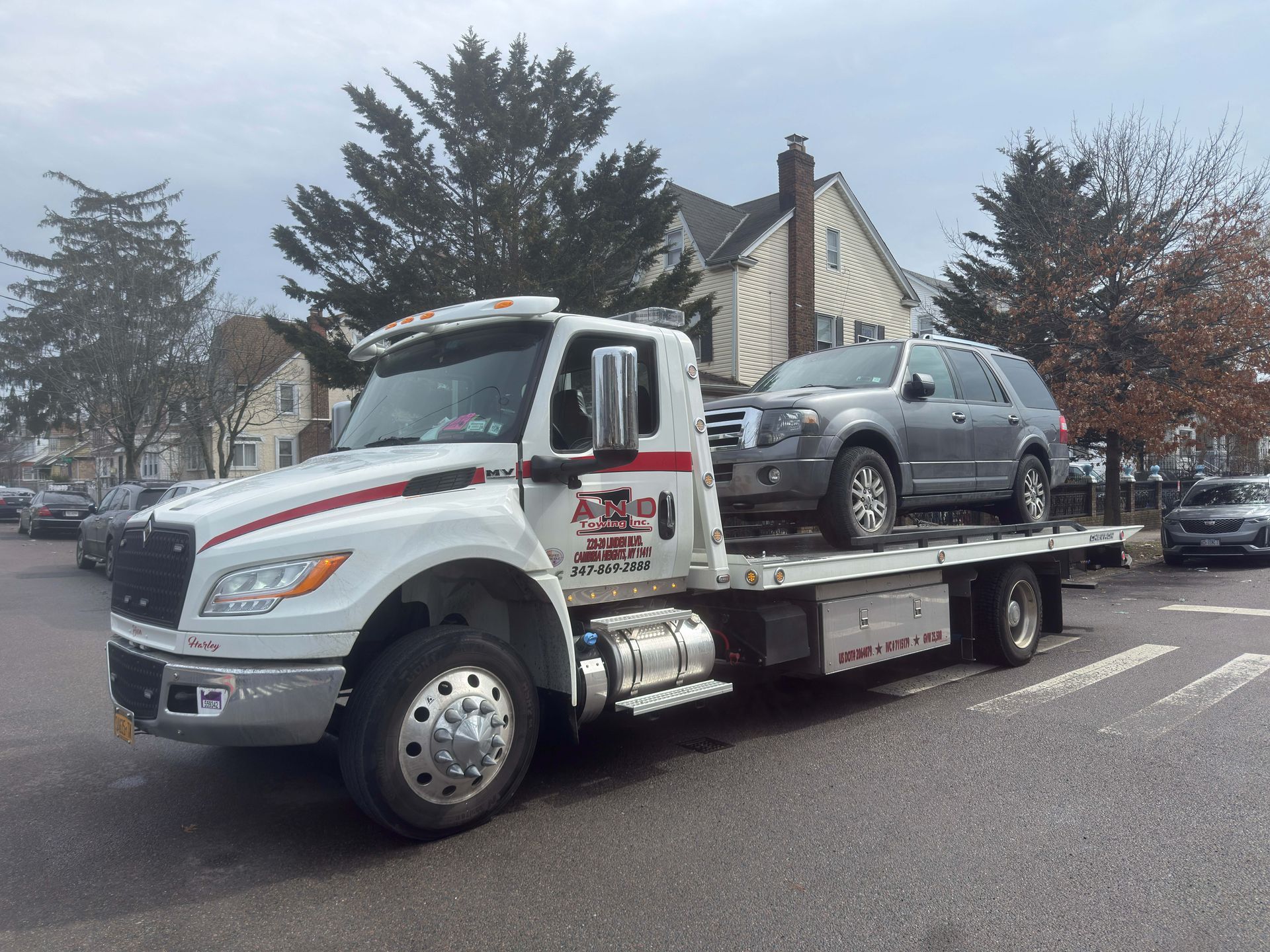 Tow truck carrying a silver SUV on a flatbed in a parking lot