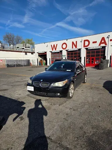 Black BMW sedan parked in front of a repair shop, 
