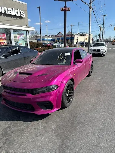 Bright pink Dodge Charger parked in front of McDonald's on a sunny day.
