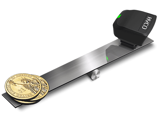A stack of gold coins sitting on top of a metal device that says taco with Hyco Ring Scanner