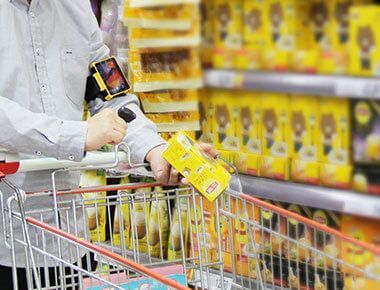 A person wearing Hyco Ring Scanner and W563 Wearable Computer is pushing a shopping cart in a grocery store.