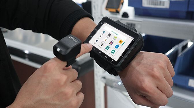 A person using a wearable computer and a ring scanner in a warehouse setting.