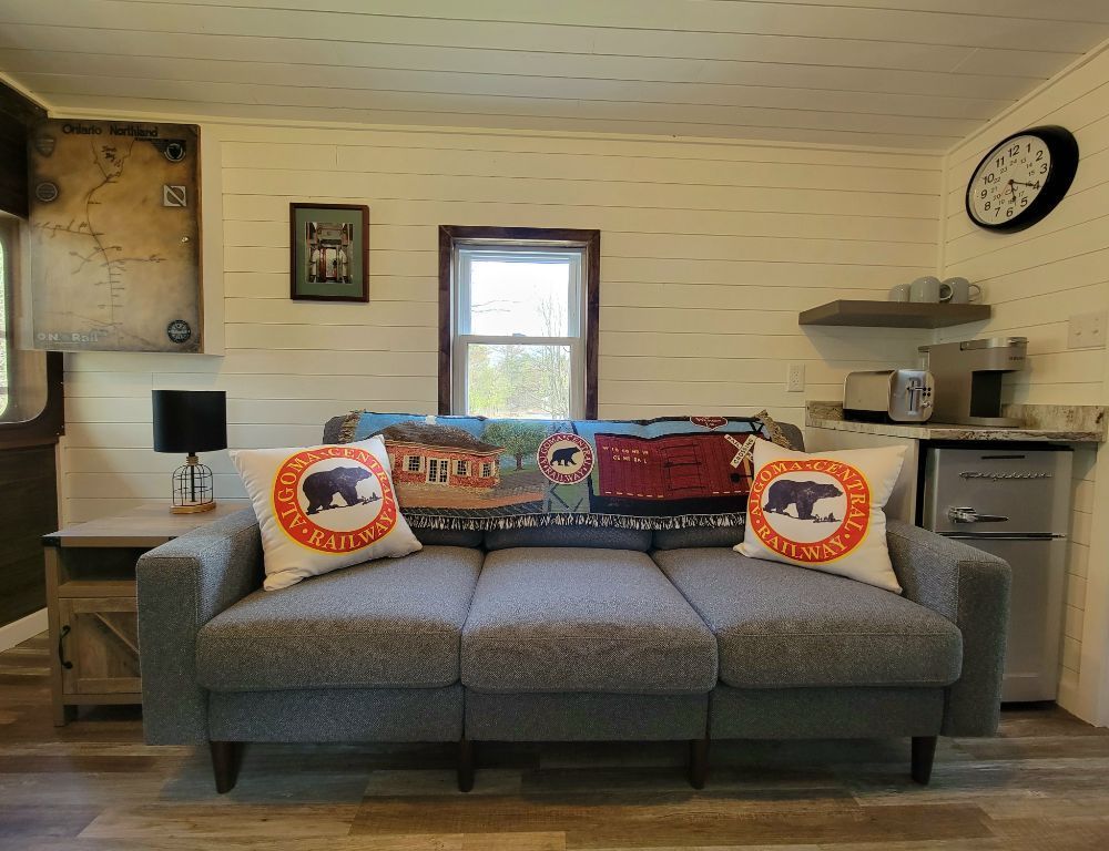 A living room with a couch and a clock on the wall.