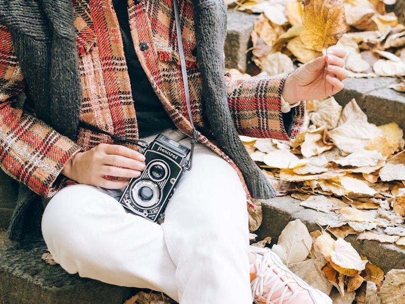 A woman is sitting on a set of stairs holding a camera.