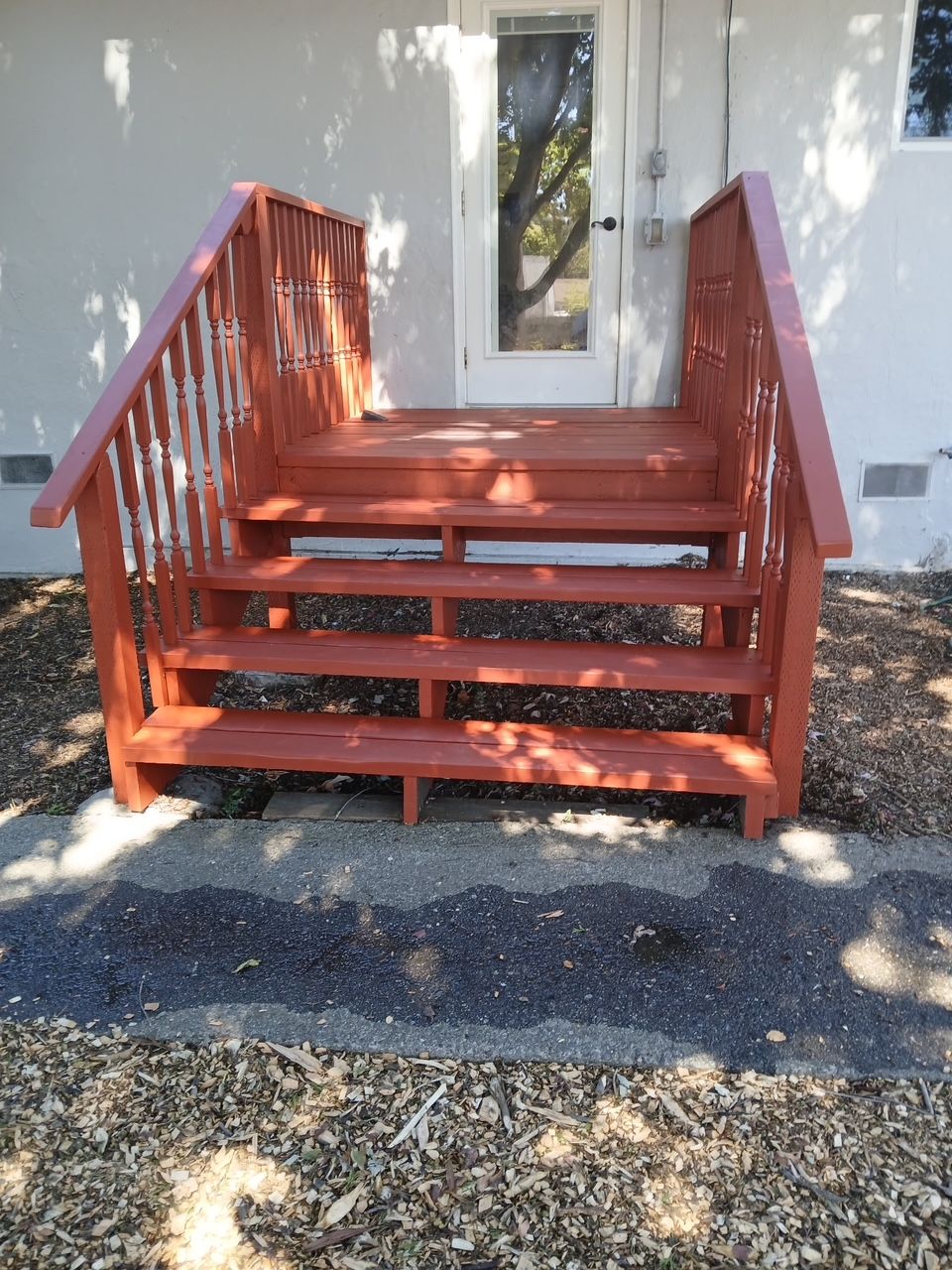  new painted Red wooden porch steps with railings beside a house and door