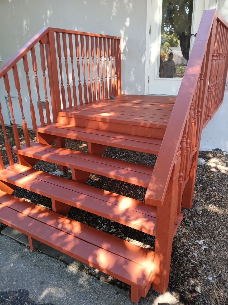  new painted Red wooden porch steps with railings beside a house and door