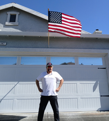 Person standing in front of a white garage with an American flag flying above it